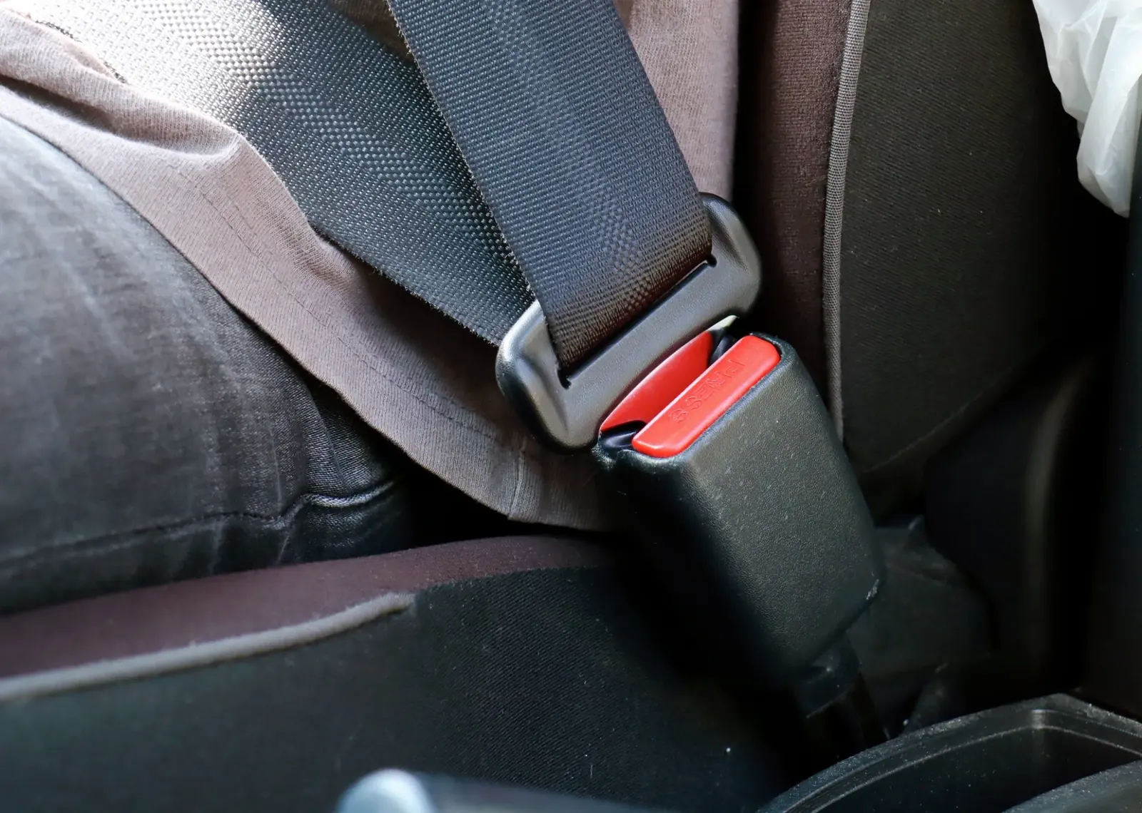 Lap section of a seat belt fastened low across the hips of a seated occupant.